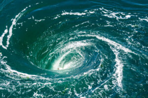 A powerful whirlpool is generated at the surface of the green waters of the river Rance by the action of a turbine of the tidal power station near Saint-Malo in Brittany, France.